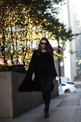 Beautiful woman model in a black long coat against the background of lanterns and pipes in Manhattan