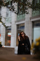 Fototapeta premium A beautiful woman in a black long coat walks through the streets of New York