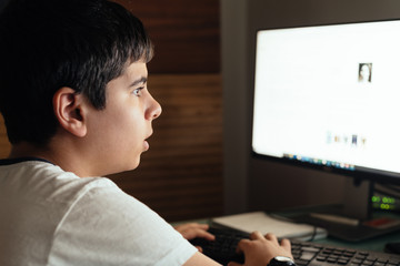 Teenager concentrated is studying at home attending online classes during the coronavirus COVID-19 pandemic quarantine