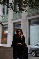 Obraz premium A beautiful woman in a black long coat walks through the streets of New York