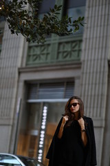 A beautiful woman in a black long coat walks through the streets of New York