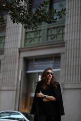 Naklejka premium A beautiful woman in a black long coat walks through the streets of New York
