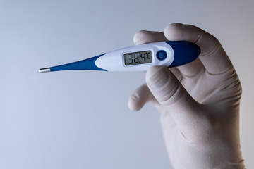 Obraz premium Hand in a medical glove holds a thermometer.