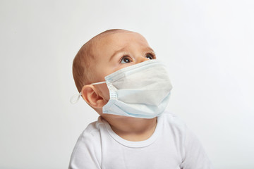An infant boy wearing a face mask on white