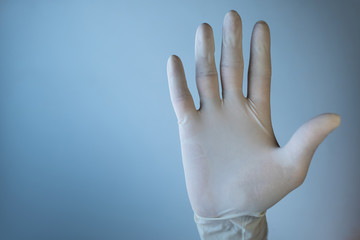 Hand in medical glove showing stop sign. Empty space.