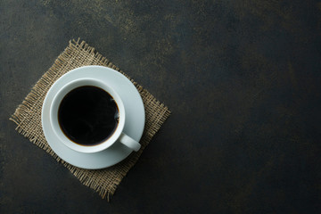 Obraz na płótnie Canvas A cup of black tea on a linen napkin. View from above. Dark background.