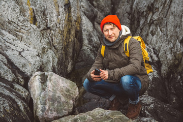 Traveler man holding smartphone in hands against the background of mountains and rocks. Place for text or advertising