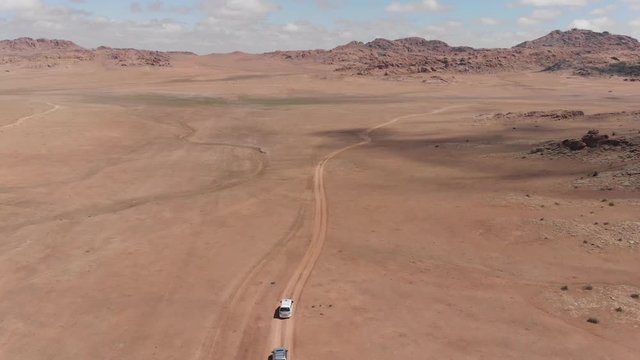 Aerial drone shot following a car in the scenic Gobi Desert, Mongolia