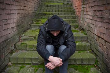 A drug addict man is sitting on the street, experiencing a drug addiction crisis. Social problems.