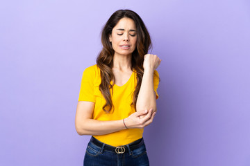 Woman over isolated purple background with pain in elbow