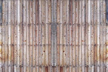 A solid wall of aged brown wooden planks with clogged nails located vertically. Concept for texture, background, interior.