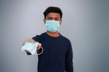 young boy wearing protective mask offering a face mask against the corona virus
