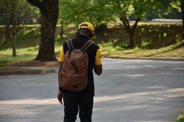 A young man with a backpack walking in the park