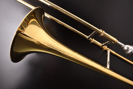 Golden trombone detail on a black wooden table