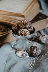 Fototapeta na wymiar Chocolate truffles with nuts. Dark, rustic and creatively lit festive liquer chocolates with cocunut and crushed nuts. ICE CREAM CUP