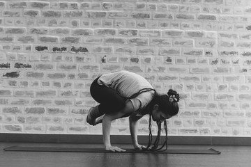 young woman doing yoga workout on yoga mat against brick wall black and white photography