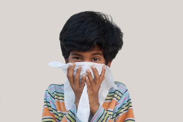 Little Indian boy blowing his nose against Corona virus
