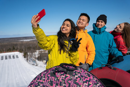 Group Of Multiracial Millenials Snow Tubing In The Winter In Canada With An Active Lifestyle