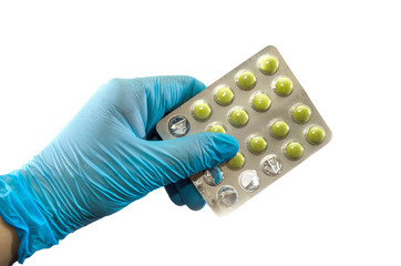 a hand in a blue glove holds a blister with pills isolated on a white background.