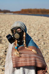 Portrait of a child in a gas mask stands near the river. Сhemical respirator. Environmental pollution. The concept of panic against viruses, biological and chemical pollution. Covid-19 virus protect.