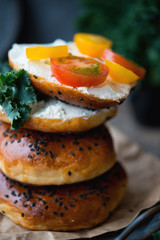 Homemade bagels with cheese and vegetables for brunch on an old wooden background