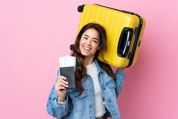 Woman over isolated blue background in vacation with suitcase and passport