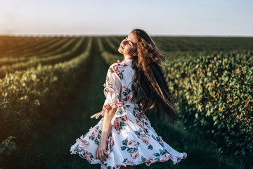 beautiful woman with long curly hair and freckles face on currant field background. Girl in a light...