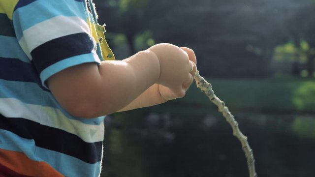 Close on toddler hands holding a stick and turning it over while observing