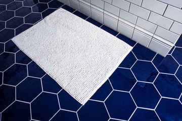 White towel on the tile blue floor. Top view on hexagon ceramic bathroom