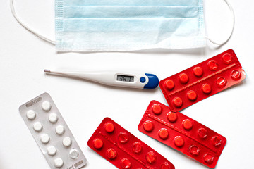 Masks, tablets, and  thermometer . The virus and the epidemic. on a white background a protective mask against coronovirus