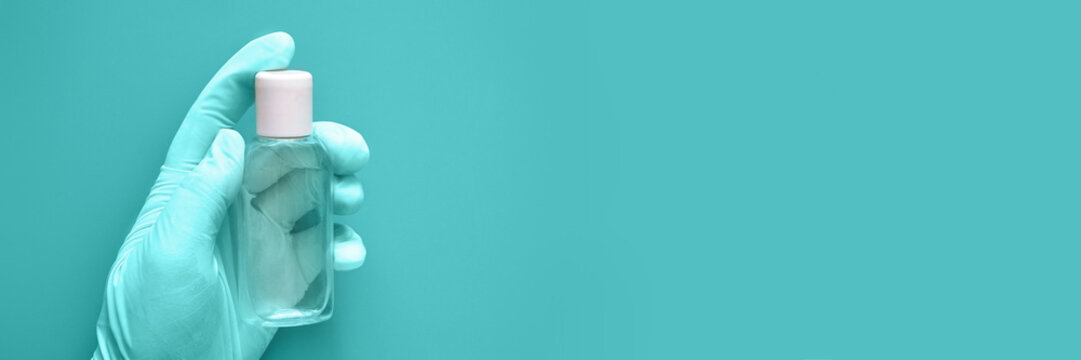 Hand in glove holding bottle of sanitizer gel banner