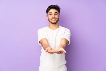 Arabian handsome man over isolated background holding copyspace imaginary on the palm to insert an...