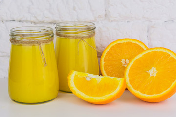 Naklejka na ściany i meble Two jars of fresh orange juice on a white background. Close-up.