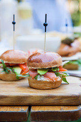 Burger with cream cheese, salted salmon, cale, avocado on wheat bun.