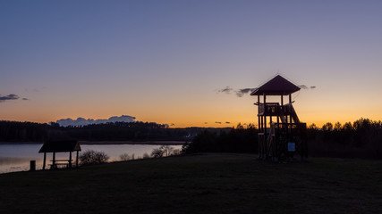 Wieża widokowa nad jeziorem na tle zachodzącego słońca. Warmia i Mazury. Polska © Marcinwarmia