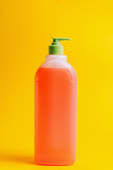 Bottled cleaners, disinfectants, sponges on a yellow background, side view