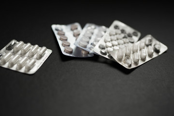 several packs of pills lying on a black background