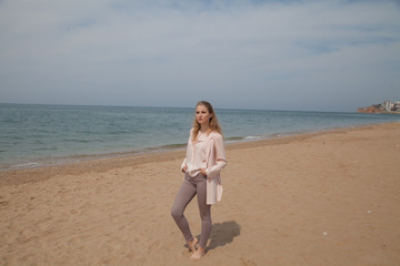 Fototapeta na wymiar Beautiful blonde woman walks on the sea beach alone