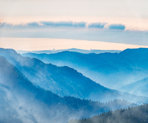 Green mountain slope. Layers of mountains in the haze during sunset. Krasnaya Polyana, Sochi, Caucasus, Russia.