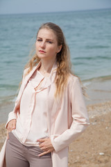 Beautiful blonde woman walks on the sea beach alone