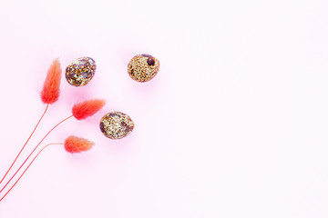 Easter background. Three pink dry spikelets and three eggs on a pink backdrop. Flat lay, copy space.
