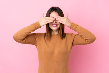 Young woman over isolated pink background covering eyes by hands