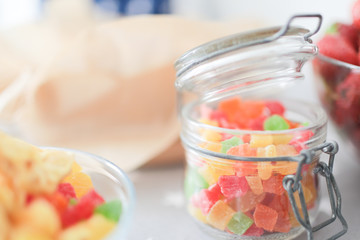 Multicolored candied fruits in a transparent stylish jar on the table.