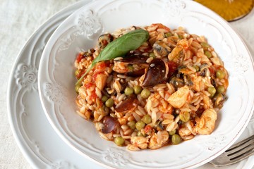 paella from orzo pasta with mussels, seashells and chicken. Seafood paella, traditional spanish dish. Paella on rustic black wooden table. Top view