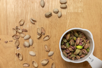 Shelled Pistachios in a White Measuring Cup on Wood Surface