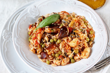 paella from orzo pasta with mussels, seashells and chicken. Seafood paella, traditional spanish dish. Paella on rustic black wooden table. Top view