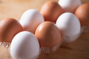 A carton of mixed brown and white eggs on a wooden background.