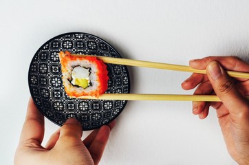 California roll held with chopsticks on ornament plate