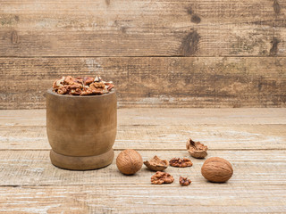 Walnuts in a wooden mortar on wooden background.
