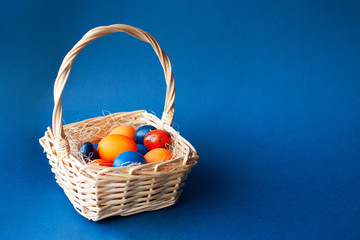 Fototapeta na wymiar Easter eggs in trendy colors in the basket on the blue background. The concept of stylish natural decoration for Easter, minimalistic, zero waste, greeting cards, etc. Copy space.